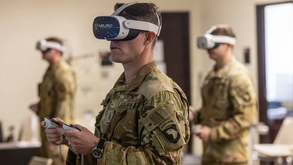 A U.S. Army soldier of the 101st Airborne Division wearing a NeuroTrainer virtual reality headset and holding hand controllers, with other headset-wearing soldiers behind