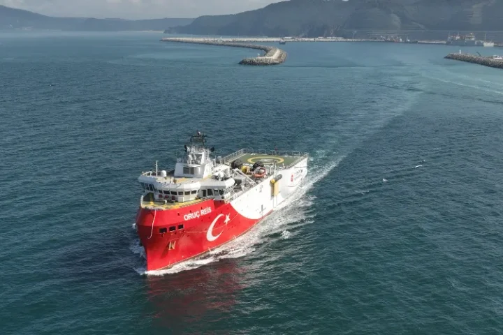 The red-hulled Turkish seismic research vessel Oruç Reis under way near a breakwater, seen from above