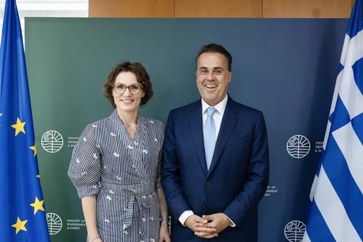Greek Minister of Environment and Energy Stavros Papastavrou stands beside EU Commissioner Jessika Roswall in front of a ministry backdrop with EU and Greek flags