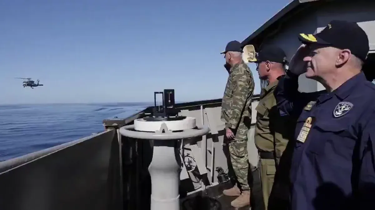 The Greek and Israeli chiefs of staff saluting on a ship's deck during the firings