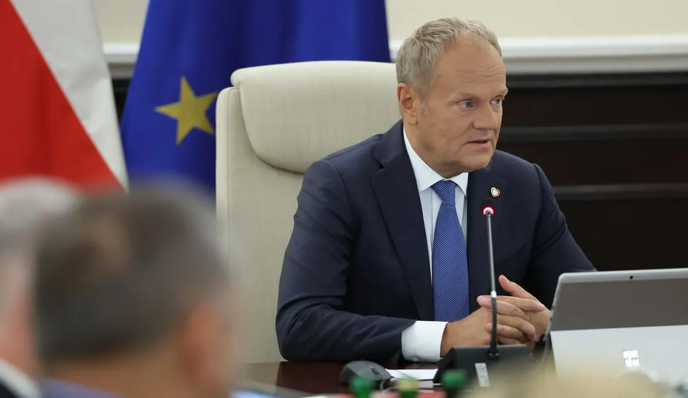 Polish Prime Minister Donald Tusk speaking at a Council of Ministers meeting, with the Polish and European Union flags behind him