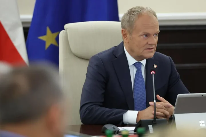 Polish Prime Minister Donald Tusk speaking at a Council of Ministers meeting, with the Polish and European Union flags behind him