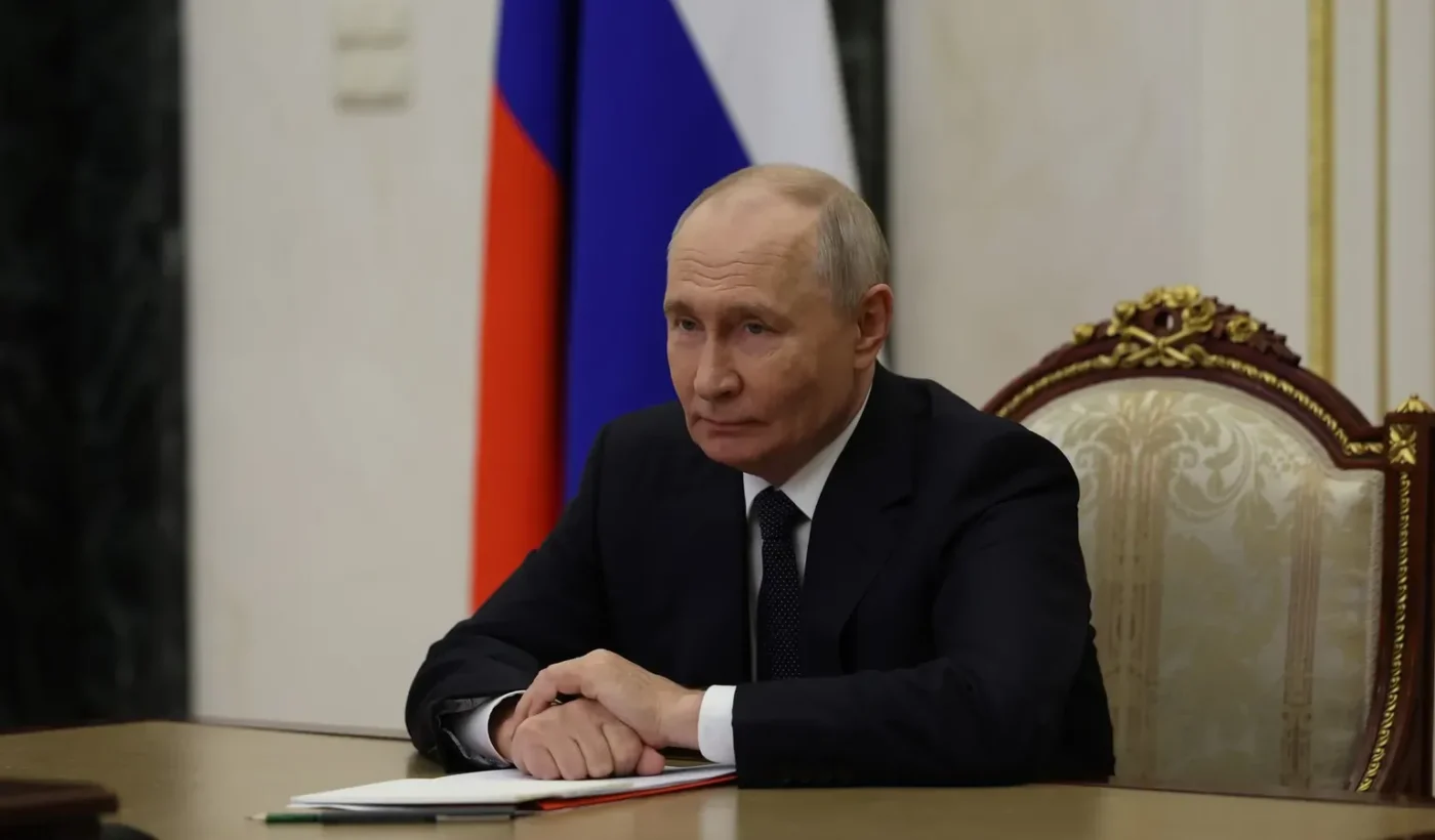 Vladimir Putin sits at a table in the Kremlin in front of a Russian flag during a Security Council videoconference