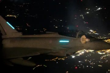 An RAF Typhoon fighter seen at night in flight over lit-up ground, in a file photo from a NATO air mission