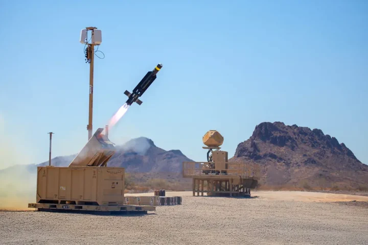 A Coyote interceptor launches from a desert test site beside a KuRFS radar