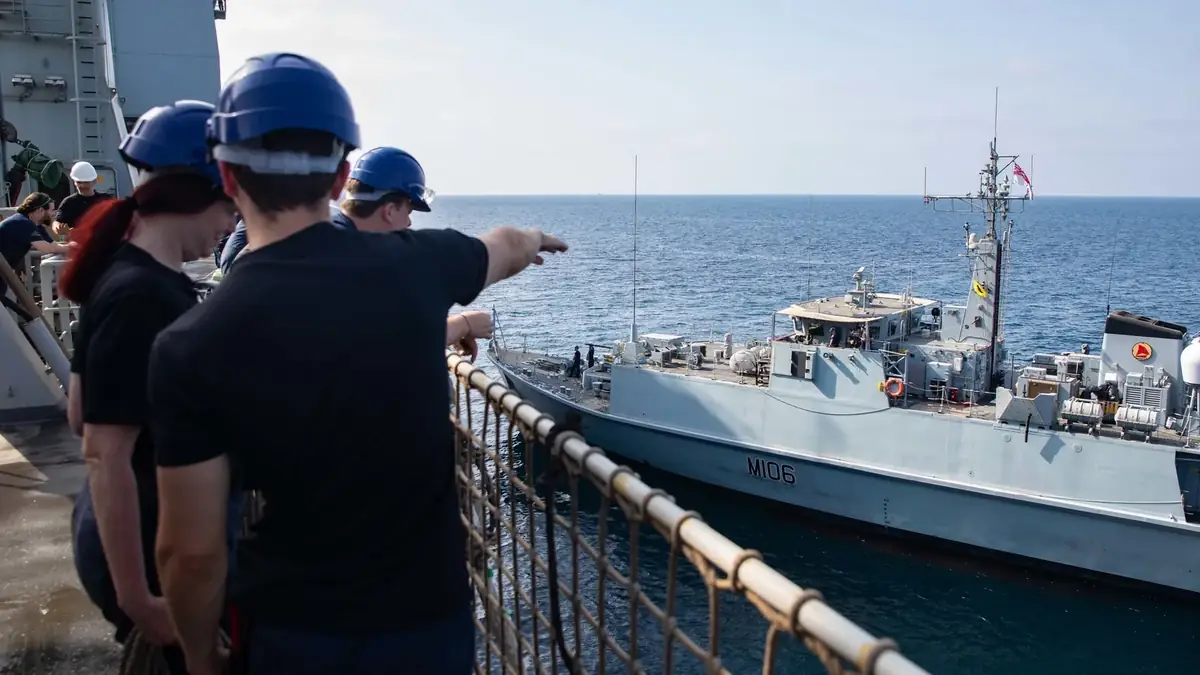 Sailors of RFA Lyme Bay replenishing the minehunter HMS Penzance at sea in the Gulf of Oman