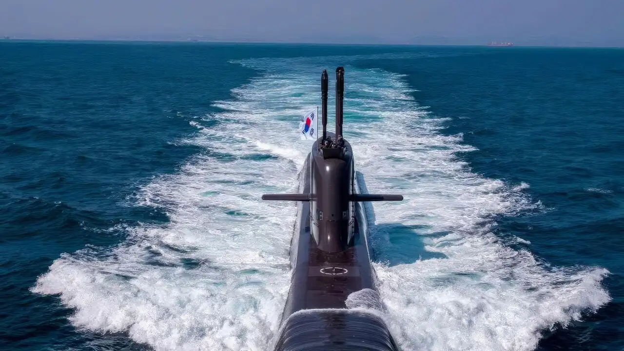 Stern view of the South Korean submarine ROKS Shin Chae-ho under way, with a wake of white water and a South Korean flag on the sail