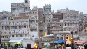 Multi-storey traditional houses with decorated windows above a market street in Sanaa