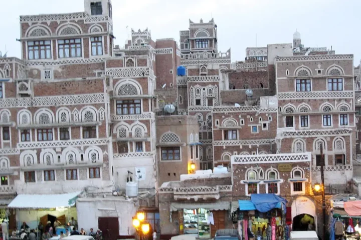 Multi-storey traditional houses with decorated windows above a market street in Sanaa