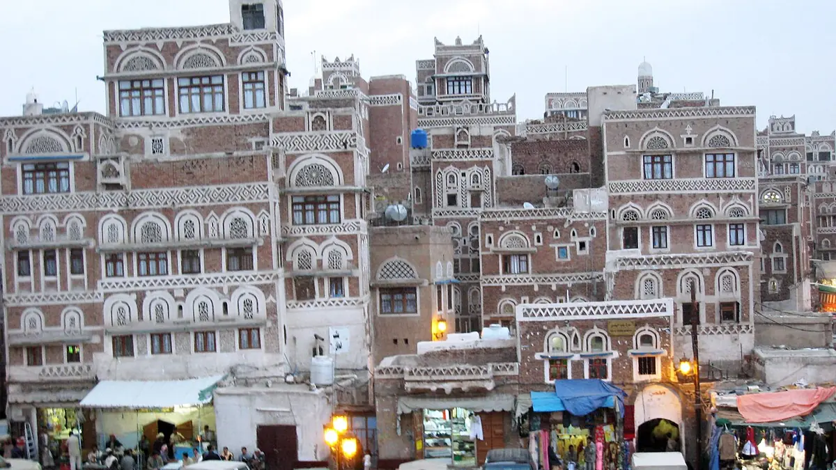 Multi-storey traditional houses with decorated windows above a market street in Sanaa