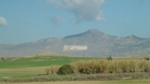 Giant flags of Turkey and the breakaway regime formed on the slope of the Pentadaktylos mountains in the occupied north of Cyprus, behind a plain