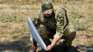 A Ukrainian soldier installing a Starlink satellite terminal outdoors