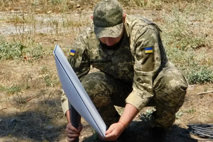 A Ukrainian soldier installing a Starlink satellite terminal outdoors