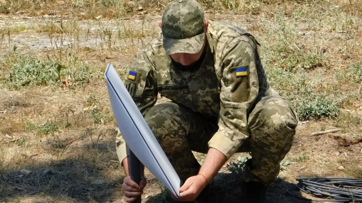 A Ukrainian soldier installing a Starlink satellite terminal outdoors
