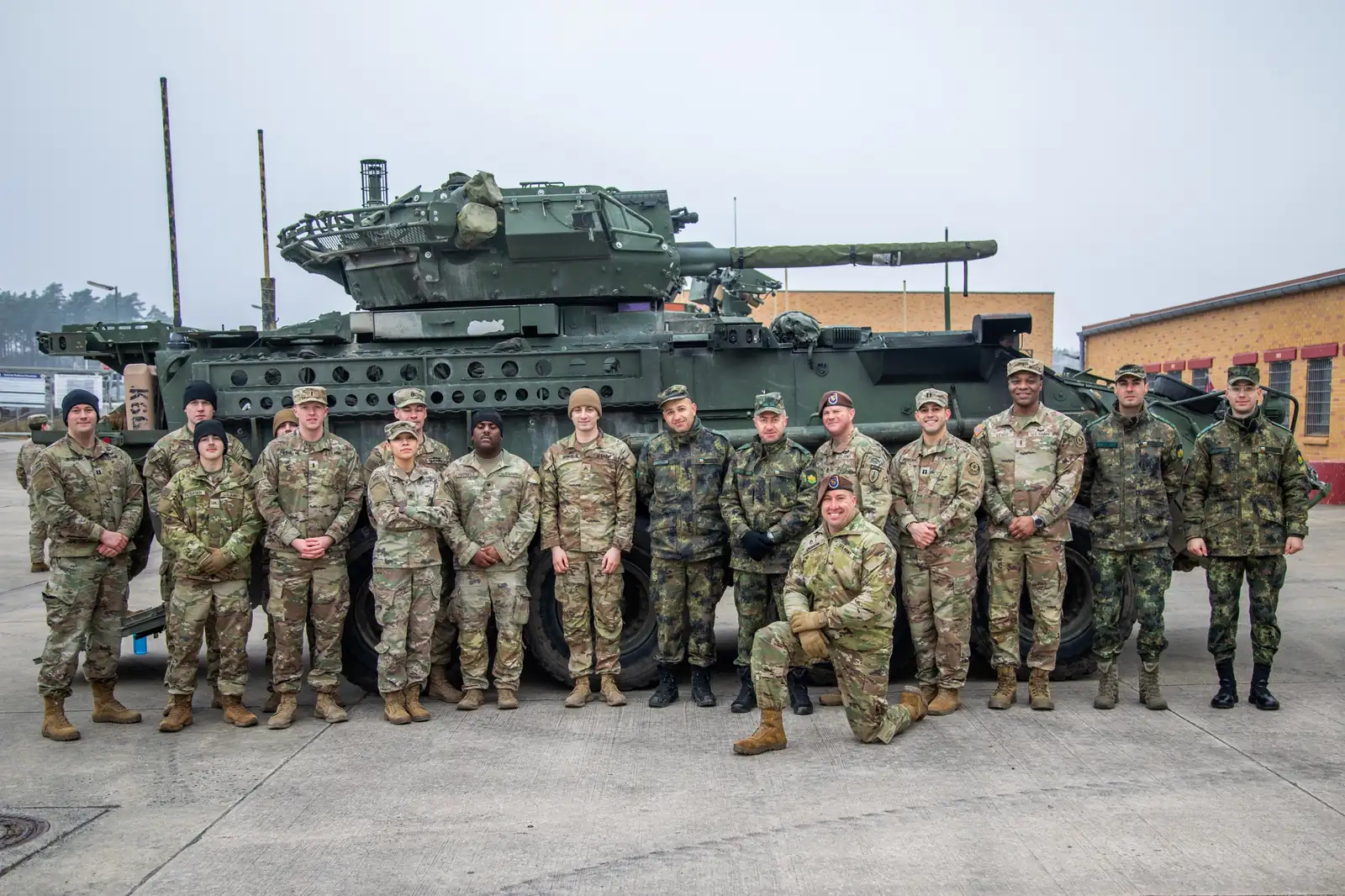 US and Bulgarian soldiers posing in front of a Stryker Dragoon with a 30 mm cannon turret