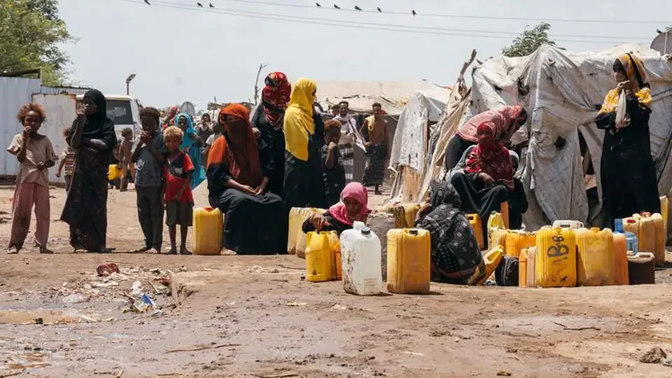 Women and children wait beside rows of yellow jerrycans at a displacement site in Yemen (file image)