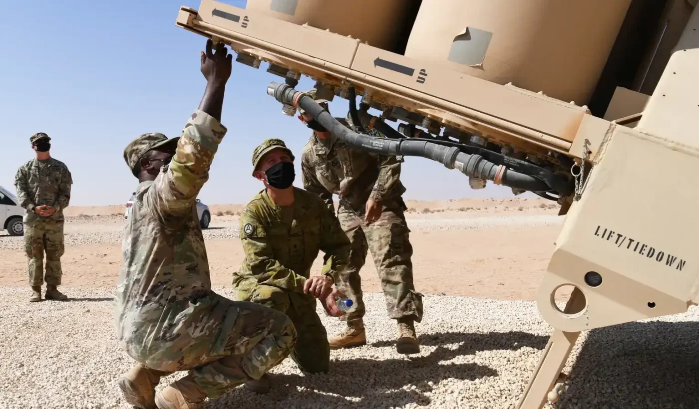 Soldiers in desert camouflage inspect a THAAD missile launcher in the Saudi desert