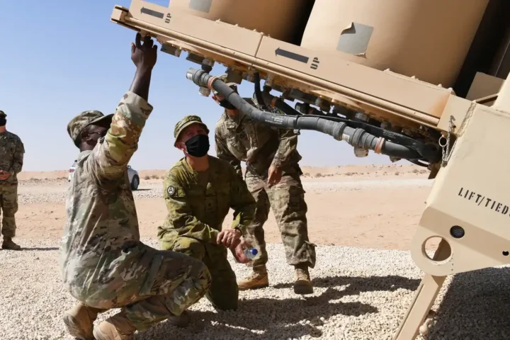 Soldiers in desert camouflage inspect a THAAD missile launcher in the Saudi desert