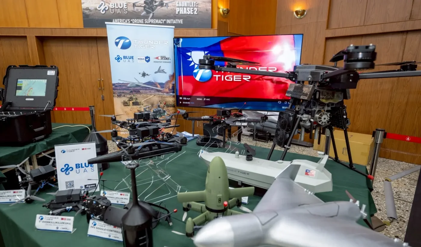 A table with various multirotor and FPV drones, a screen with the Taiwanese flag and a Blue UAS banner