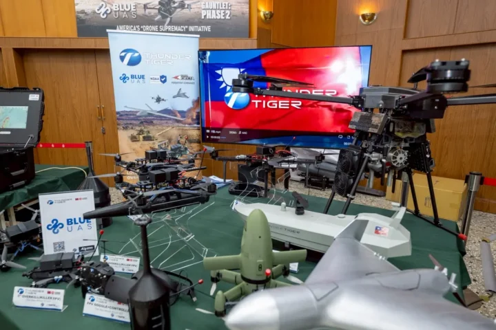 A table with various multirotor and FPV drones, a screen with the Taiwanese flag and a Blue UAS banner