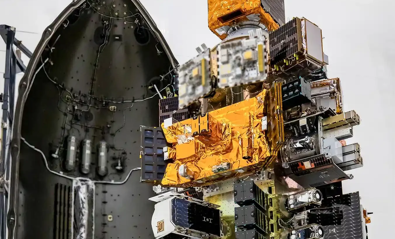 Small satellites mounted on a dispenser beside the open half of a Falcon 9 fairing