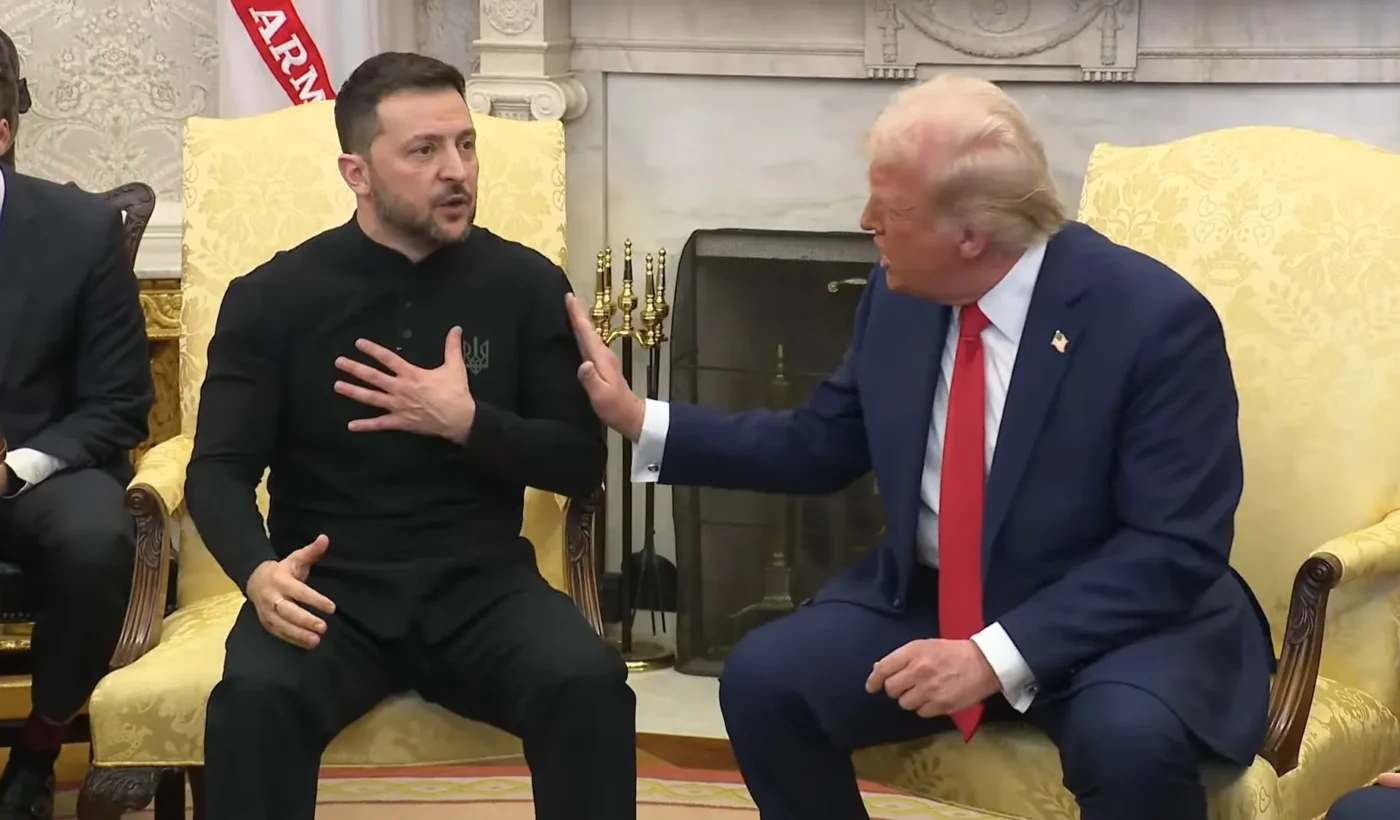 Donald Trump and Volodymyr Zelensky sit facing each other in yellow armchairs in the Oval Office, Trump leaning towards Zelensky with his hand raised