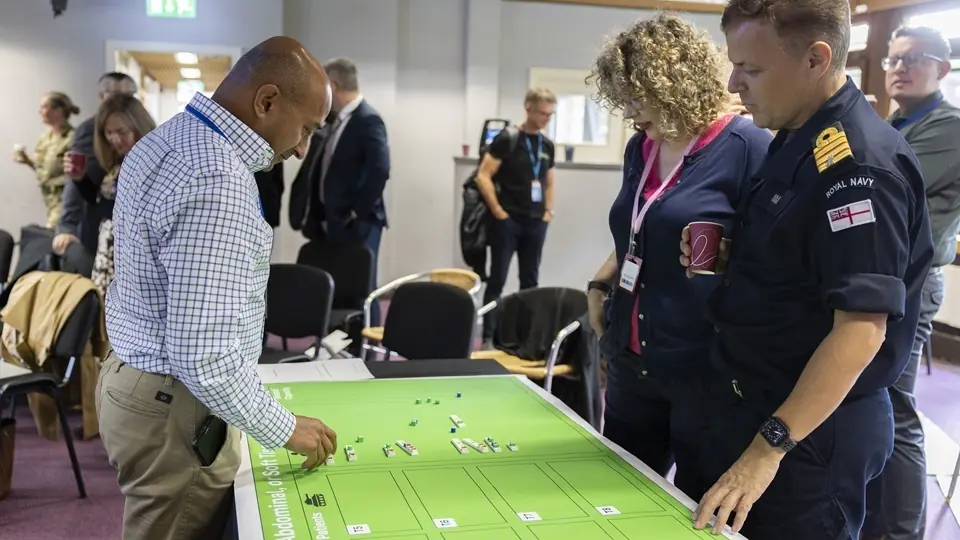 Participants including a Royal Navy officer study a map-style game board during the UK medical war-game