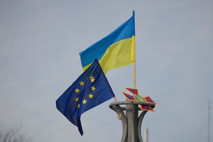 The flags of Ukraine and the European Union flying side by side on a pole