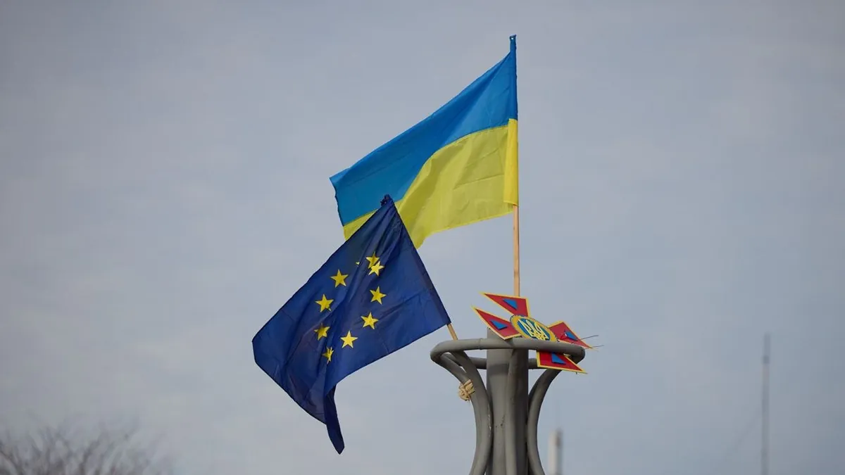 The flags of Ukraine and the European Union flying side by side on a pole