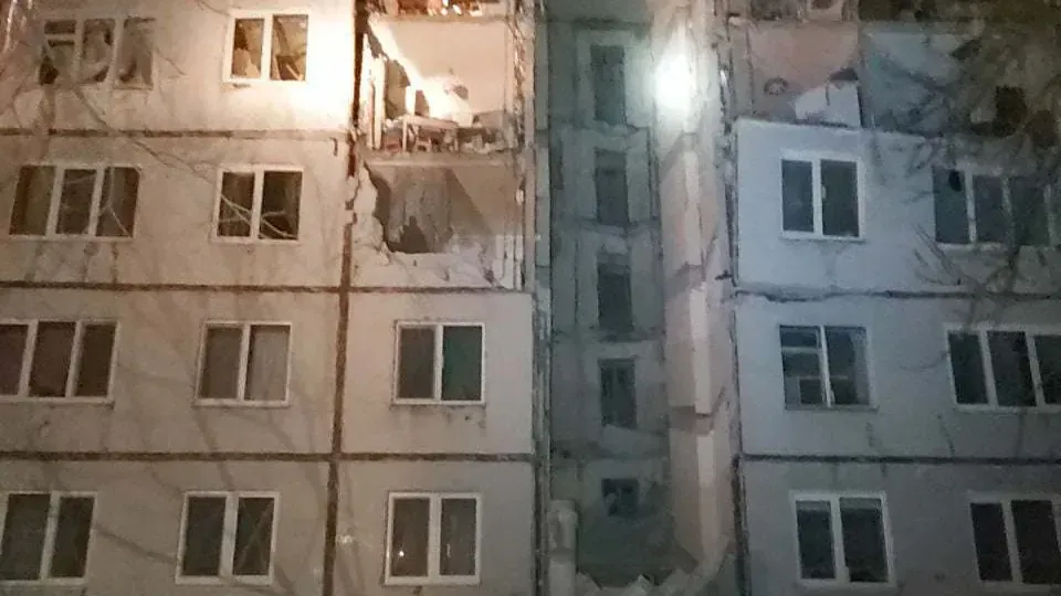 Night view of an apartment block in Kharkiv with damaged balconies and shattered windows