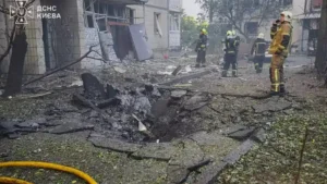Rescuers beside a crater and a damaged building in Kyiv after a Russian drone strike on 9 September 2026