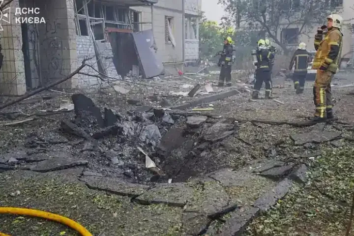Rescuers beside a crater and a damaged building in Kyiv after a Russian drone strike on 9 September 2026