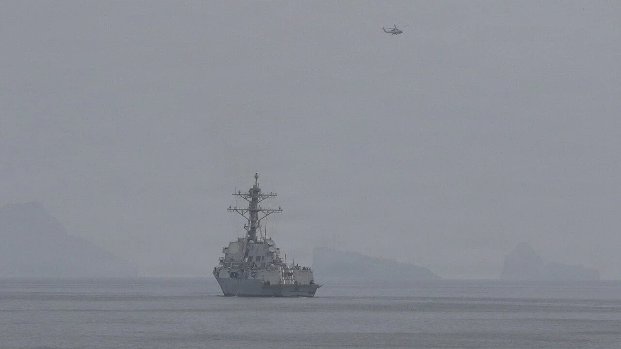 U.S. Navy destroyer and helicopter in haze during an April 2026 Hormuz mine-clearance mission