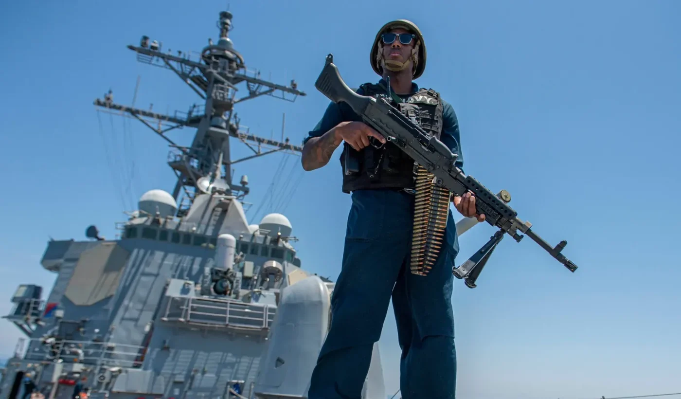 A U.S. Navy sailor stands watch with an M240B machine gun on the deck of the destroyer USS Paul Hamilton while transiting the Strait of Hormuz