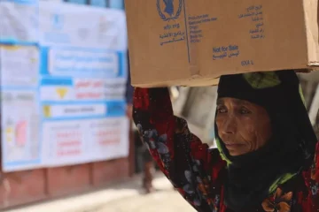 A woman carries a box of WFP food rations on her head in Jabal Habashi, Taiz governorate, Yemen