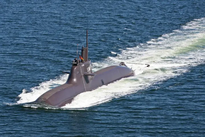 A German Type 212A submarine sailing on the surface, with its sail and rudder visible