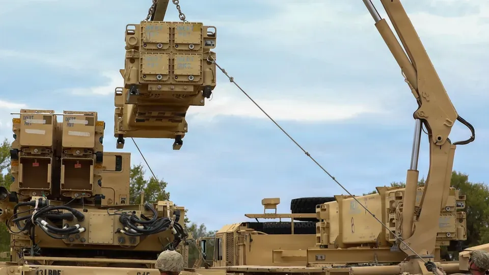 Soldiers use a crane to load a reload canister of Patriot missiles onto a launcher
